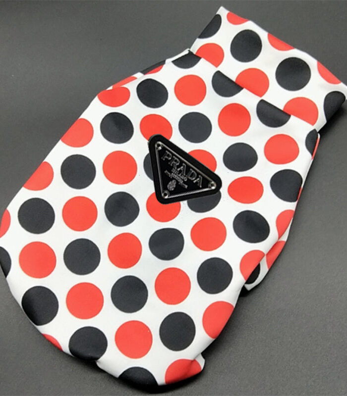 White polka dot dog jacket flat lay showing Pawda triangle logo and zip closure