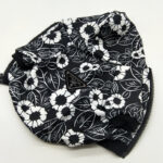Close-up black floral print dog hoodie showing Pawda triangle logo and pocket detail