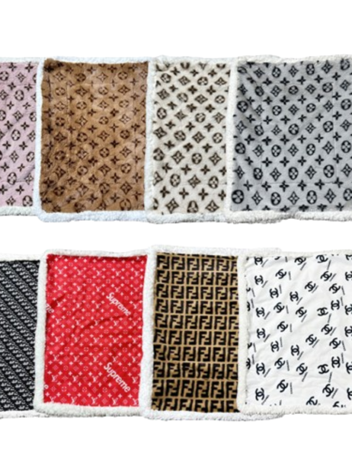 Designer dog bed collection showing 8 different parody brand patterns including Louis Vuitton, Supreme, Chanel and Fendi inspired designs with white sherpa borders