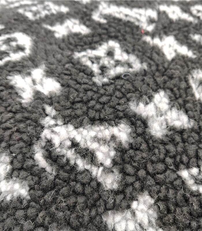 Close-up of charcoal fleece fabric with white V monogram pattern dog bed texture