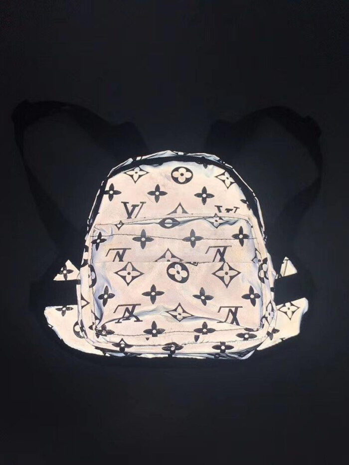 Reflective dog backpack with V monogram pattern showing adjustable straps and buckles