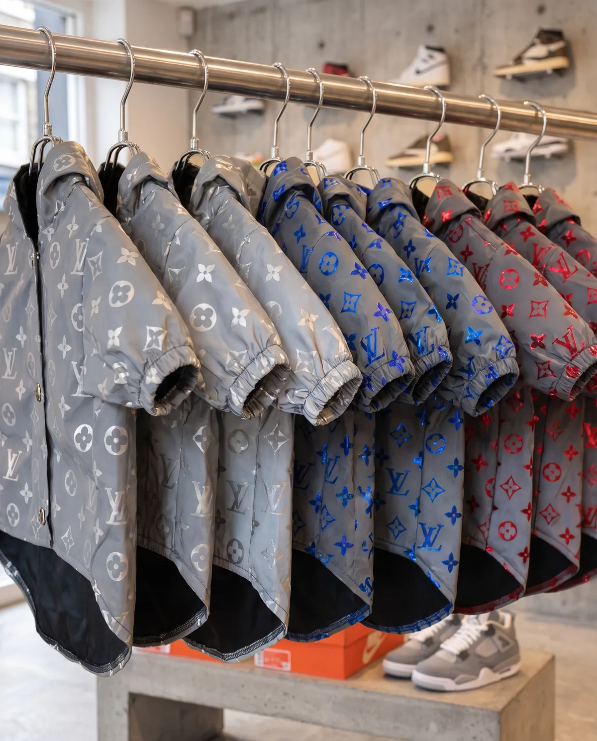 Chewy V Reflective Windbreakers in silver, blue and red on a chrome rack in a sneaker shop, flash off