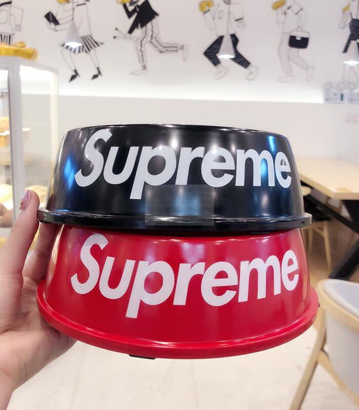 Red dog bowl with white Supreme branding being held in hand