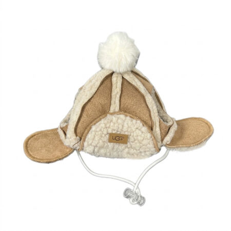 Brown sherpa-lined dog winter hat with white pom pom and ear flaps UGG style on white background